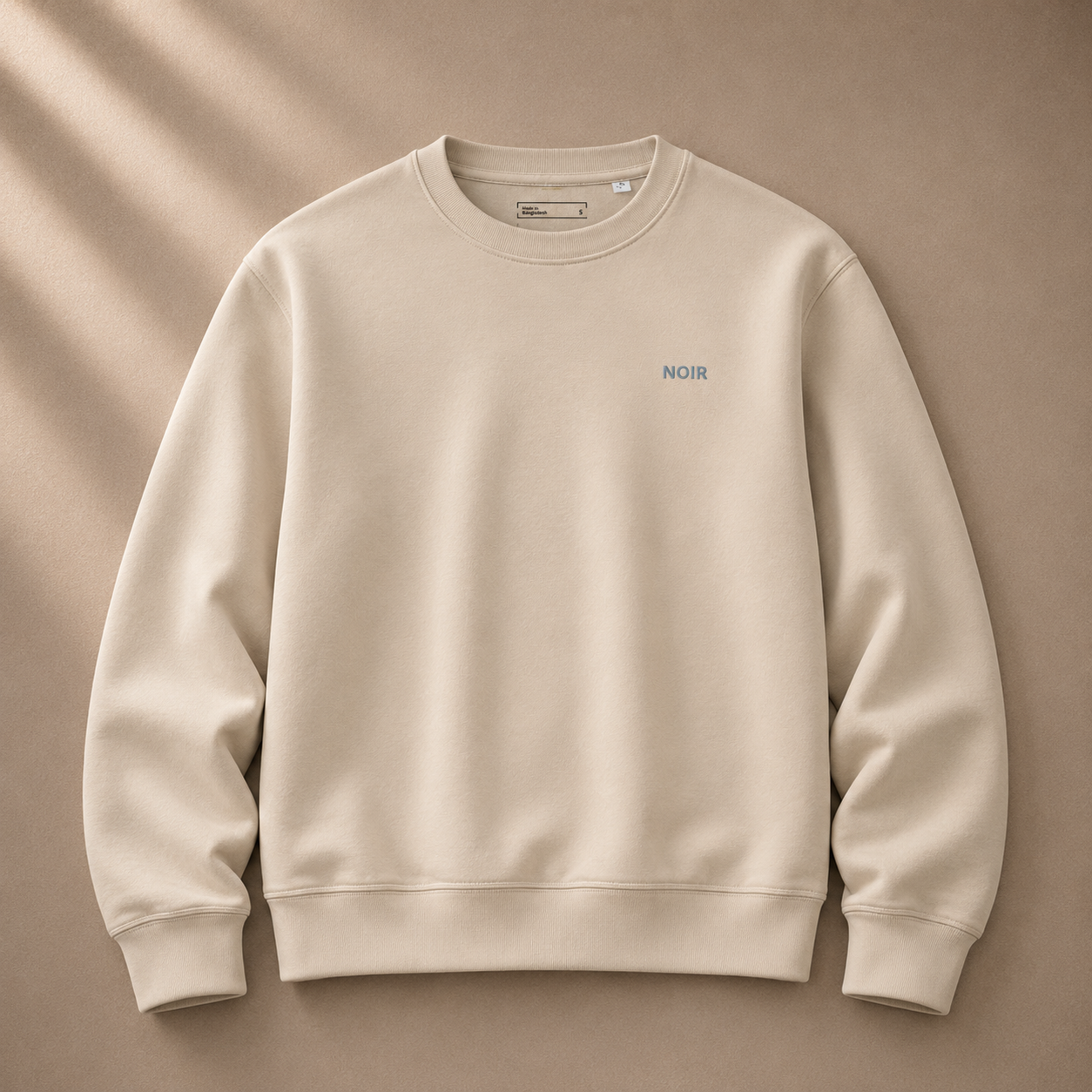 Dress 2 Impress Ltd D2I Noir Essential Sweatshirt in Desert Dust, showing a casual beige and black clothing item with a relaxed fit.
